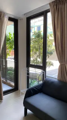 a living room with a couch in front of a window at POP Heritage Residence in Bangkok