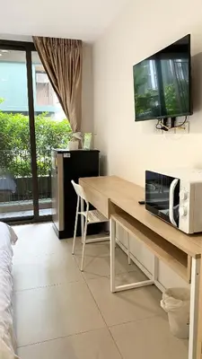 a living room with a desk with a television on the wall at POP Heritage Residence in Bangkok
