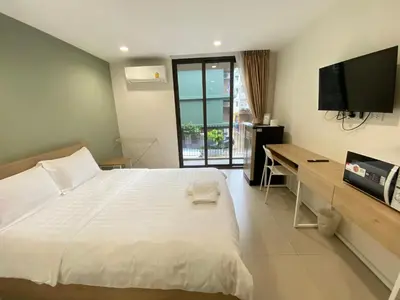 a bedroom with a large white bed and a flat screen tv at POP Heritage Residence in Bangkok