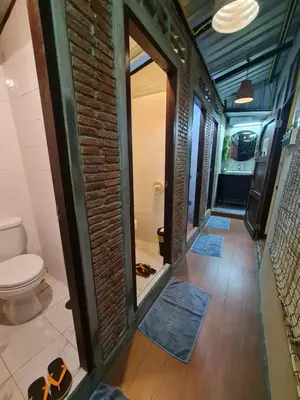 a bathroom with a toilet and a brick wall at Non House Bangkok บ้านนอนโฮสเทล in Bangkok