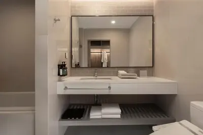 a white bathroom with a sink and a mirror at Staybridge Suites Bangkok Sukhumvit by IHG in Bangkok