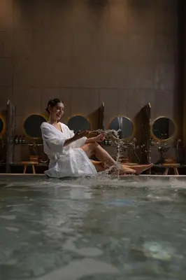 a woman sitting on the edge of a swimming pool at Staybridge Suites Bangkok Sukhumvit by IHG in Bangkok