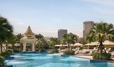 a swimming pool with a gazebo and palm trees at Chatrium Grand Bangkok in Bangkok