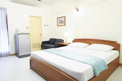 a bedroom with a bed and a chair at Phawana Sweet Hotel in Bangkok