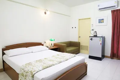 a bedroom with a bed and a chair in a room at Phawana Sweet Hotel in Bangkok