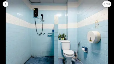 a blue tiled bathroom with a toilet and a shower at Flourish Apartments in Bangkok