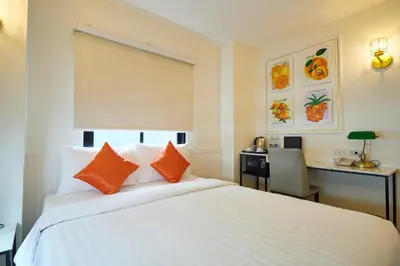 a bedroom with a large white bed with orange pillows at Rose Apple Hotel in Bangkok