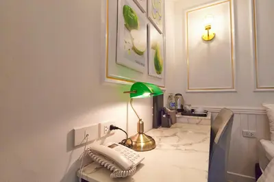 a room with a desk with a green lamp on it at Rose Apple Hotel in Bangkok