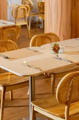 a wooden table with chairs and a plate of food on it at Arck Hotel in Bangkok