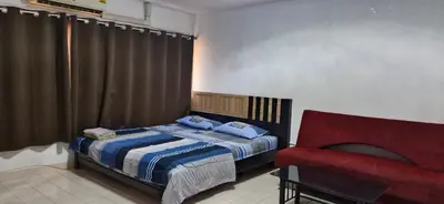 a bedroom with a bed and a red chair at ห้องพักรายวัน เมืองทองธานี เรือนศรีตรัง in Ban Bang Phang