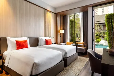 a hotel room with two beds and a large window at Villa Deva Resort & Hotel Bangkok in Bangkok