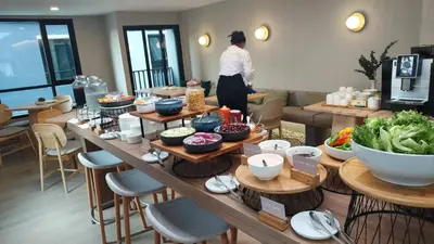 a woman standing in a room with a table of food at Wellness Stay & Hotel Sukhumvit 107 in Bangna
