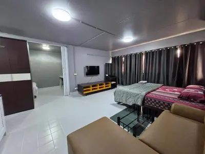 a room with a bed and a couch and a tv at ห้องใหญ่-ห้องพักรายวัน เมืองทองธานี เรือนศรีตรัง in Nonthaburi