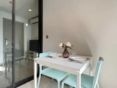 a white table with blue chairs and a vase with flowers at Asok - Din Daeng Apartment in Bangkok