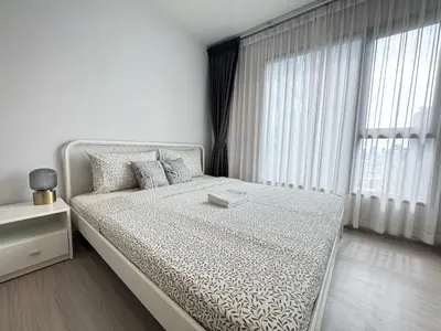 a white bedroom with a large bed and a window at Asok - Din Daeng Apartment in Bangkok