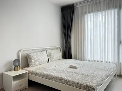 a white bedroom with a bed and a window at Asok - Din Daeng Apartment in Bangkok