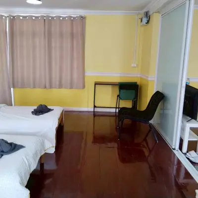 a room with two beds and a chair and a window at Aran Colonial House & Cafe Ngamwongwan in Ban Bang Khen (1)