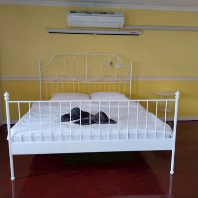 a white bed sitting in a room with a wall at Aran Colonial House & Cafe Ngamwongwan in Ban Bang Khen (1)