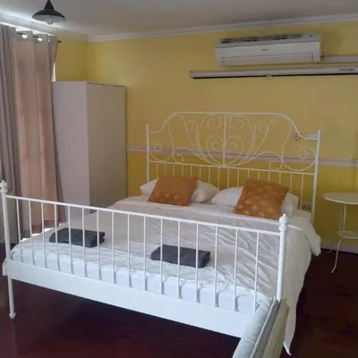 a bedroom with a white bed with pillows on it at Aran Colonial House & Cafe Ngamwongwan in Ban Bang Khen (1)