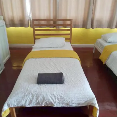 a bedroom with two beds with white and yellow at Aran Colonial House & Cafe Ngamwongwan in Ban Bang Khen (1)
