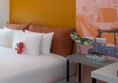 a teddy bear sitting on top of a bed at Jono Bangkok Asok Hotel in Bangkok