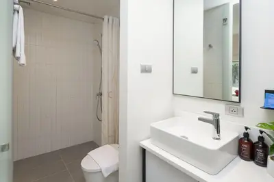 a white bathroom with a sink and a shower at Jono Bangkok Asok Hotel in Bangkok
