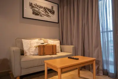 a living room with a chair and a coffee table at VOQUE Hotel & Serviced Residence Sukhumvit 51 in Bangkok