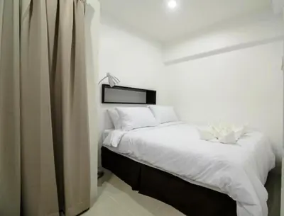 a bedroom with a bed with white sheets at UMA Residence in Bangkok