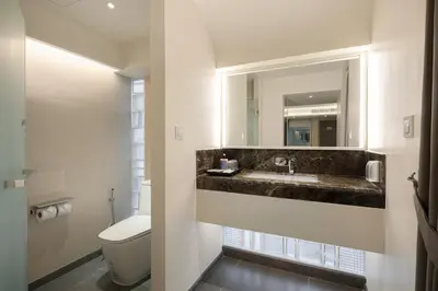 a bathroom with a sink and a toilet and a mirror at YANH Ratchawat Hotel in Bangkok