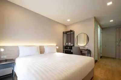 a bedroom with a large white bed and a mirror at fyn park hotel in Makkasan