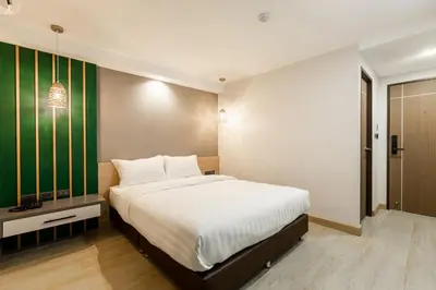 a bedroom with a large bed with a green accent wall at City Park Hotel Bangkok Pratunam by PCL in Bangkok