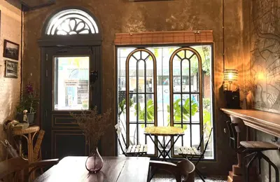 a dining room with a table and two windows at Central Old Town Cottage in Bangkok