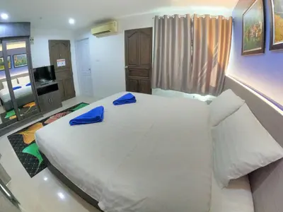 a bedroom with a large white bed with blue slippers on it at Poonsuk Place Hotel in Bangkok Noi