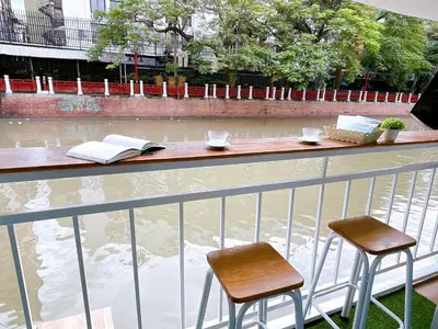 a balcony with two chairs and a table and books at Lively and cozy canal house ,Entire house in Bangkok
