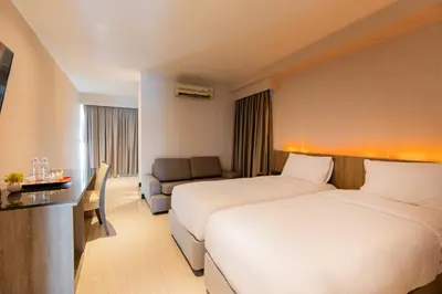 a hotel room with two beds and a couch at Sukhothai Hotel and Residence Ratchada in Bangkok