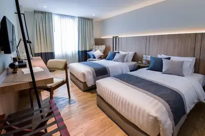 a hotel room with two beds and a chair at Bella B Hotel in Nonthaburi