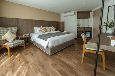 a bedroom with a large bed and a chair at Bella B Hotel in Nonthaburi