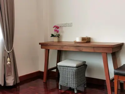 a wooden table in a room with a wicker stool at Sri Ayuttaya Guesthouse in Bangkok