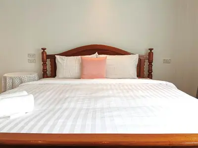 a large bed with white sheets and pink pillows at Sri Ayuttaya Guesthouse in Bangkok