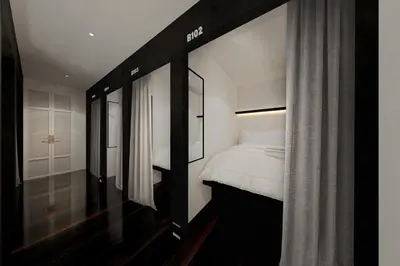 a bedroom with a bed with white sheets and a window at Forgotten Hostel Silom in Bang Rak