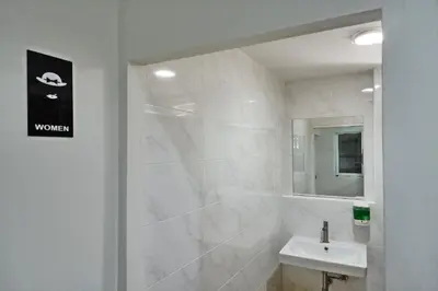a white bathroom with a sink and a mirror at Forgotten Hostel Silom in Bang Rak