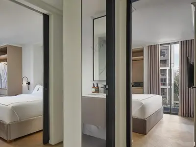 a bedroom with a bed and a bathroom with a mirror at The Alberti Hotel - Sukhumvit 31 in Bangkok