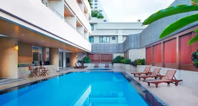a swimming pool with chairs and a building at S.M. GRANDE RESIDENCE in Bangkok