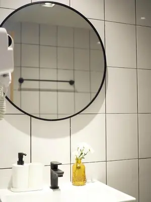 a bathroom with a mirror and a yellow vase with flowers at Ascella Bangkok Hotel in Makkasan