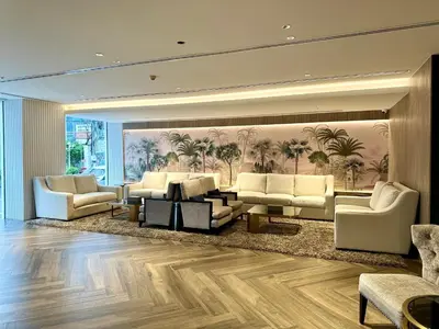 a living room with white furniture and palm trees at Grace At Five by Grace Hotel Bangkok in Bangkok
