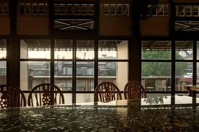 a dining room with a table and chairs and windows at neil niwas in Bangkok