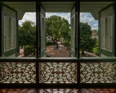 an open window with a view of a park seen through it at neil niwas in Bangkok