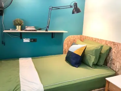 a green couch with a lamp and a blue wall at CB's - Cheap Boutique Bangkok in Bangkok