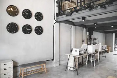 a room with clocks on the wall and tables at The Cube Hostel Khaosan in Bangkok