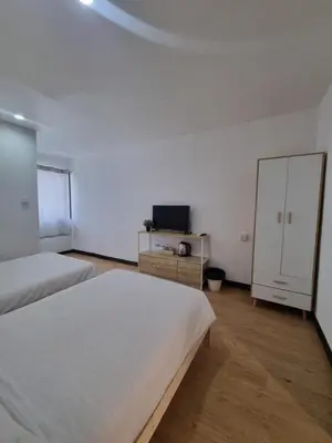 a bedroom with two beds and a dresser with a tv at Owl's Nest suk 30 in Bangkok